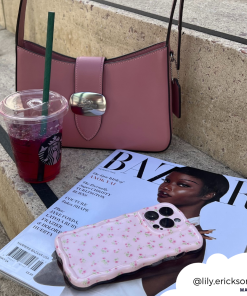 A pink handbag, a Starbucks drink with a green straw, a Harper's Bazaar magazine featuring a woman on the cover, and Coconut Lane's Wavy Phone Case in Ditsy Floral Pink are placed on concrete steps. The Instagram handle @lily.erickson is positioned in the bottom right corner within a white cloud shape.