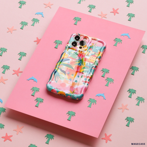 The Wavy Phone Case - Portofino Dreams by Coconut Lane, with its Italian seaside theme and colorful pastel patterns, is placed on a pink surface adorned with small illustrations of palm trees, starfish, and dolphins. This extra protective case adds a lively touch to the overall beachy design.
