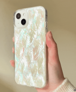 A hand holding an iPhone with Coconut Lane's Real Natural Shell Phone Case - White, which features a glossy, iridescent finish and a subtle feather-like pattern. The background is softly blurred. The case has a luminous, pearlescent sheen with hints of pink, blue, and green reflecting off its surface.