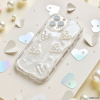 Introducing the Pearly Hearts Phone Case - Clear from Coconut Lane for the iPhone 15. This extra protective case showcases raised, shiny heart designs against a pearlescent, swirled background. It elegantly complements any look while your phone rests on a beige, glittery surface adorned with metallic heart confetti and pearl-like beads. Combining style and safety seamlessly, it's the perfect blend of functionality and glamour.