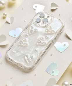 Introducing the Pearly Hearts Phone Case - Clear from Coconut Lane for the iPhone 15. This extra protective case showcases raised, shiny heart designs against a pearlescent, swirled background. It elegantly complements any look while your phone rests on a beige, glittery surface adorned with metallic heart confetti and pearl-like beads. Combining style and safety seamlessly, it's the perfect blend of functionality and glamour.