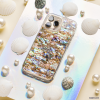 The Coconut Lane Real Natural Shell Phone Case - Black, showcasing an exquisite abalone shell-patterned design, is elegantly displayed on a reflective holographic surface. Surrounded by white seashells, spherical pearls, and textured grey stones, it crafts an immersive marine-inspired aesthetic.