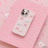A Coconut Lane Pearly Hearts Phone Case - Pink, designed for the iPhone 15 and adorned with four white hearts and three pink bows, lies flat against a pink background featuring white heart patterns and scattered heart-shaped confetti. The phone's rear cameras are visible through cutouts in the case.