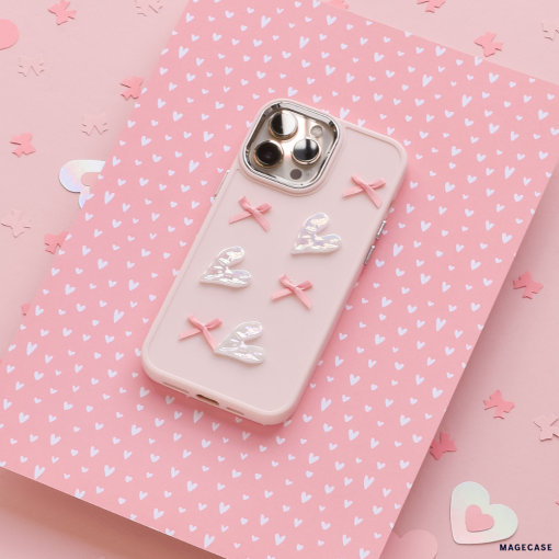 A Coconut Lane Pearly Hearts Phone Case - Pink, designed for the iPhone 15 and adorned with four white hearts and three pink bows, lies flat against a pink background featuring white heart patterns and scattered heart-shaped confetti. The phone's rear cameras are visible through cutouts in the case.