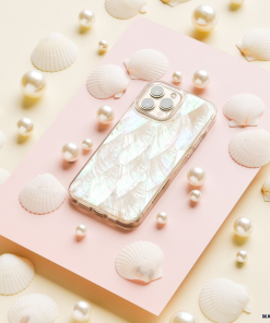 A smartphone with a pearlescent Real Natural Shell Phone Case - White by Coconut Lane is placed on a pink rectangular surface. The scene is decorated with assorted white seashells and scattered pearls, arranged on a cream-colored background.