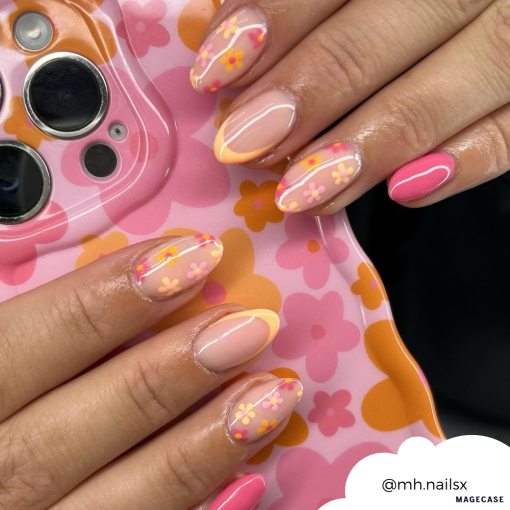 A close-up of hands with manicured nails featuring a vibrant design. The nails showcase pink and orange flower patterns along with yellow French tips. The Wavy Phone Case - Pink & Orange Bloom by Coconut Lane, held in one hand, complements the nail art perfectly with its matching floral design. Image credit: @mh.nailsx.