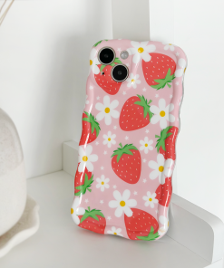 The Wavy Phone Case - Berry Cute Strawberry by Coconut Lane, adorned with red strawberries and white flowers, is propped against a white surface. A beige vase is partially visible in the background.