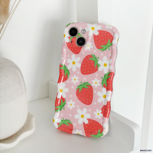 The Wavy Phone Case - Berry Cute Strawberry by Coconut Lane, adorned with red strawberries and white flowers, is propped against a white surface. A beige vase is partially visible in the background.