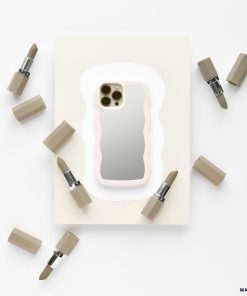 A stylish iPhone adorned with a sleek Curvy Mirror Phone Case in Cream from Coconut Lane lies on a white and beige background, surrounded by six lipsticks with beige casings. The composition seamlessly blends tech and beauty products, creating a minimalist and elegant visual.