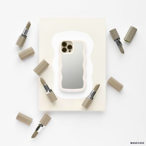 A stylish iPhone adorned with a sleek Curvy Mirror Phone Case in Cream from Coconut Lane lies on a white and beige background, surrounded by six lipsticks with beige casings. The composition seamlessly blends tech and beauty products, creating a minimalist and elegant visual.