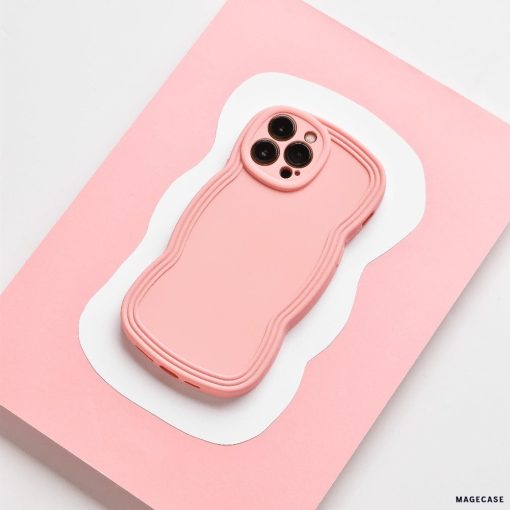 A strawberry-colored smartphone with a matching wavy-edged case rests on a pink and white abstract-patterned surface. The matte finish of the Coconut Lane NAKD Curvy Phone Case - Strawberry adds an elegant touch, while its highly protective design ensures the three-lens rear camera setup remains safe and secure.