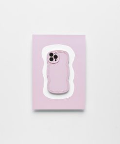 A smartphone with a Blueberry protective case from Coconut Lane lies on top of a light pink and white wavy-edged mat against a plain white background. The lightweight NAKD Curvy Phone Case highlights the phone camera cutout, making it both stylish and functional.
