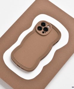 A lightweight, brown NAKD Curvy Phone Case - Coffee from Coconut Lane with a wavy design lies on a flat, brown and white, wavy-edged surface. The case has precise cutouts for the camera lenses and appears highly protective. The background contrasts with the NAKD Curvy Phone Case, highlighting its unique shape and design.