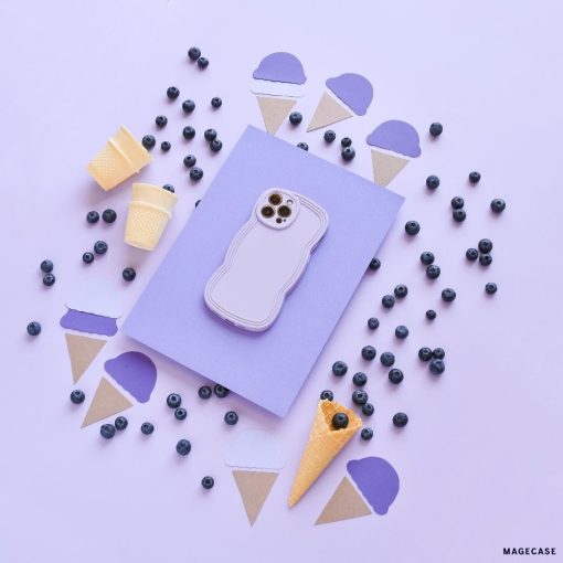 A pastel purple phone in a Coconut Lane NAKD Curvy Phone Case - Blueberry is placed on a light purple surface, surrounded by blueberries and cutouts of ice cream cones. Two small empty waffle cones and two yellow disposable cups also accompany the arrangement, all in a visually pleasing layout.