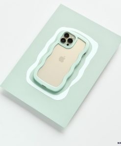 A gold iPhone, identified as an iPhone15, is encased in the rugged and wavy-edged Coconut Lane Curvy Phone Case in Mint. It's placed on a light green rectangular surface with a precise cutout that fits the phone perfectly. The camera lenses and Apple logo remain visible through the protective case.