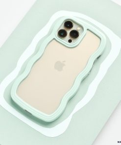 A beige iPhone 15 with three camera lenses on the back is placed on a mint green surface. The phone is encased in a Coconut Lane Curvy Phone Case - Mint, perfectly matching the surface color.
