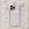 The Pearls & Bows Phone Case by Coconut Lane showcases a protective design adorned with iridescent white fabric, featuring elegant pearl-like bows and beads. The background is accentuated with petite, white bow-shaped ornaments and scattered pearl-like decorations, perfectly enhancing the sophisticated and delicate theme of this iPhone15 case.