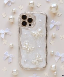 The Pearls & Bows Phone Case by Coconut Lane showcases a protective design adorned with iridescent white fabric, featuring elegant pearl-like bows and beads. The background is accentuated with petite, white bow-shaped ornaments and scattered pearl-like decorations, perfectly enhancing the sophisticated and delicate theme of this iPhone15 case.