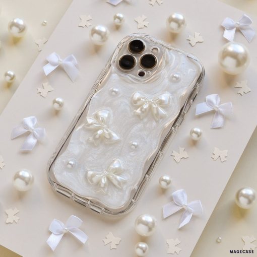 The Pearls & Bows Phone Case by Coconut Lane is adorned with white ribbon bows, pearls, and star-shaped confetti. This protective phone case showcases a pearlescent design featuring three 3D white bows and small pearl accents, all set against an elegant light-colored background.