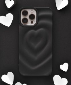 The Melting Heart Phone Case - Matte Black by Coconut Lane, featuring a 3D heart design, is displayed at the center of the image. Surrounding the phone case are several white and black heart-shaped cutouts, set against a dark background.
