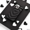 A smartphone encased in Coconut Lane's Melting Heart Phone Case - Matte Black sits on a black surface, surrounded by scattered black and white heart-shaped cutouts. The image emphasizes a monochromatic theme with a focus on the phone and the heart shapes.