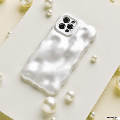 An iPhone with a glossy, ripple-patterned white case is displayed on a white rectangular surface. Surrounding the phone are scattered white pearls and Coconut Lane's 3D Pearl Phone Case - White, adding a touch of elegance to the composition.