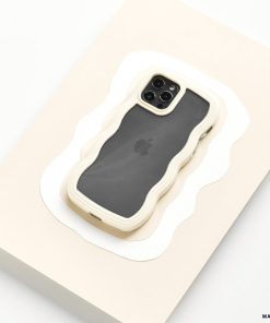 A smartphone encased in the Curvy Phone Case - Cream from Coconut Lane is set against a white and beige abstract background. The phone's rear camera, featuring multiple lenses, is visible, and the Apple logo can faintly be seen through the design on the back of the iPhone 15 case.