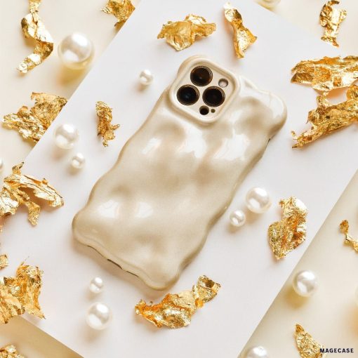 Displayed on a flat surface, surrounded by decorative gold foil fragments and scattered pearl beads, is the textured, glossy beige 3D Pearl Phone Case - Gold from Coconut Lane. This stylish and luxurious case features a wavy design and has precise cutouts for the camera lenses.