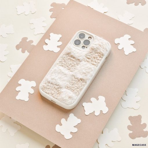 A Cosy Teddy Phone Case in Vanilla Biscuit by Coconut Lane is placed on a beige sheet of paper. Surrounding the phone are small, white bear-shaped cutouts scattered on a cream-colored surface, creating a cozy and whimsical scene.