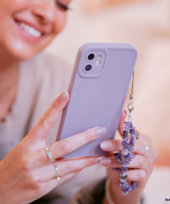 A person with light pink nail polish from the NAKD spring collection smiles while holding a smartphone adorned with the 