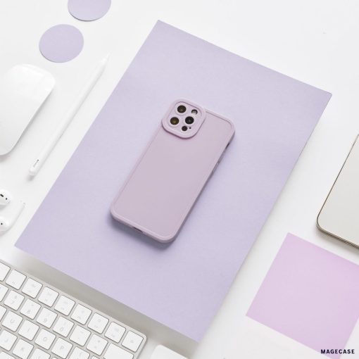 A lilac-colored smartphone case from the Coconut Lane NAKD collection is placed on a matching lilac sheet of paper. Surrounding it are various office supplies, including a white keyboard, a white pencil, a white wireless earbud, and a partially visible laptop. The setting is minimalistic and clean.