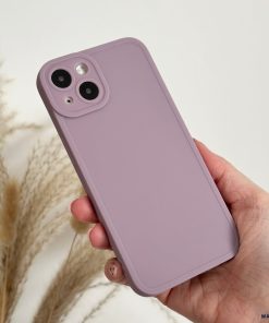 A hand holding a smartphone with a Coconut Lane NAKD Phone Case in lilac from the spring collection. The phone, boasting full camera protection with two rear lenses, is set against a background of beige pampas grass, creating a minimalistic and aesthetically pleasing composition perfect for pastel favorites.