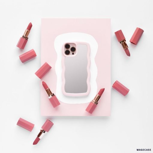 A phone with the Curvy Mirror Phone Case in pink from Coconut Lane lies on a pink and white background, surrounded by eight pink lipstick tubes, some with their caps off, revealing the lipsticks. The composition is minimalistic with a soft color palette.