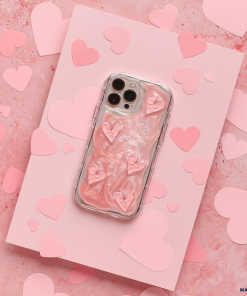 A smartphone encased in Coconut Lane's Shimmer Pink Hearts Phone Case is placed on a pink card surrounded by paper hearts. The sparkling pink hearts on the glossy, raised texture of the case stand out against the pink background adorned with various heart shapes.