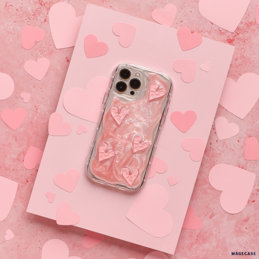 A smartphone encased in Coconut Lane's Shimmer Pink Hearts Phone Case is placed on a pink card surrounded by paper hearts. The sparkling pink hearts on the glossy, raised texture of the case stand out against the pink background adorned with various heart shapes.