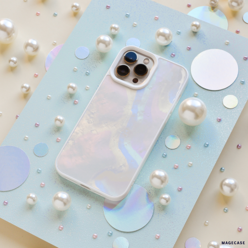 An iridescent iPhone with a Coconut Lane Mother of Pearl Phone Case is displayed on a light blue sparkly board. The background is adorned with various sizes of pearls and holographic circles, creating a whimsical and elegant arrangement.