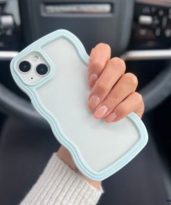 A person's hand is holding up a white iPhone15 encased in a light blue, protective Curvy Phone Case by Coconut Lane. The case highlights the back of the phone with its dual camera lenses. In the background, you can see the interior of a car, including the steering wheel and dashboard. The person's nails are neatly manicured with a natural look.