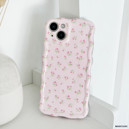 A close-up of a smartphone encased in the Wavy Phone Case - Ditsy Floral Pink by Coconut Lane, featuring delicate ditsy floral patterns in pink. The phone is propped up against a white wall next to a white vase, creating a clean and minimalist aesthetic.