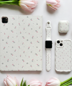 A neatly arranged flat lay showcases tech accessories with a matching delicate ditsy floral pattern: an iPad cover, a smartwatch band, an extra protective AirPods case, and the Wavy Phone Case - Ditsy Floral White from Coconut Lane. Pink tulips border the layout, adding a touch of elegance and harmony to the scene.